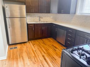 Chicago apartment for rent - A kitchen with a stainless steel refrigerator and wooden floors.