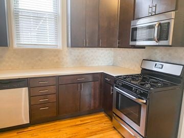 Chicago apartment for rent - A kitchen with a black stove top oven and a black microwave above it.