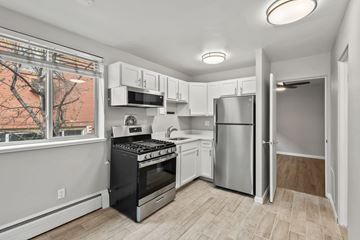 Denver apartment for rent - A kitchen with white cabinets and a black stove top oven.
