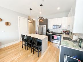 Chicago apartment for rent - a kitchen with white cabinets and a large island with a marble countertop
