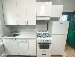 Chicago apartment for rent - A white kitchen with a stove, sink, and cabinets.