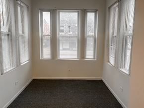 Chicago apartment for rent - A room with a carpeted floor and three windows covered with blinds.