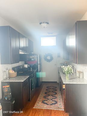Chicago apartment for rent - A kitchen with dark wood cabinets and a rug on the floor.