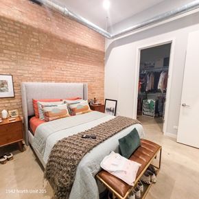 Chicago apartment for rent - A bedroom with a large bed and a brick wall.