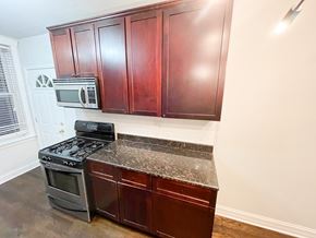 Chicago apartment for rent - A kitchen with dark wood cabinets and a black stove top oven.