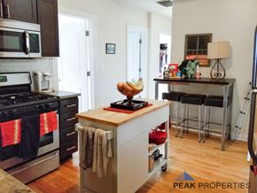 Chicago apartment for rent - a kitchen with a island and a stove and a bar with stools