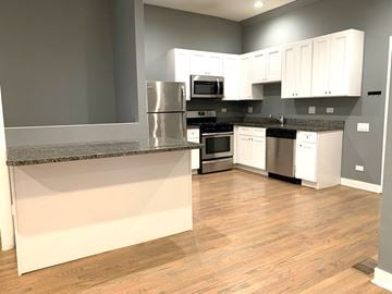 Chicago apartment for rent - A kitchen with white cabinets and a granite countertop.