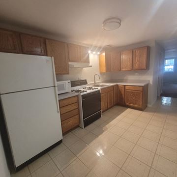 Chicago apartment for rent - A kitchen with white appliances and wooden cabinets.