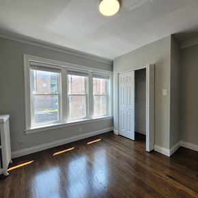 Chicago apartment for rent - A room with a wood floor and a window with a view of a building across the street.