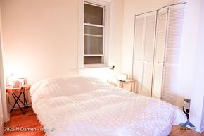 Chicago apartment for rent - A bedroom with a large bed and a window with blinds.