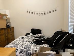 Chicago apartment for rent - A messy bedroom with a bed, dresser, and a cardboard box on the floor.