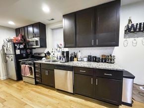 Chicago apartment for rent - A kitchen with dark brown cabinets and a white tile backsplash.