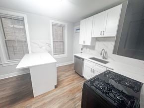 Chicago apartment for rent - A kitchen with a black stove top oven and white cabinets.