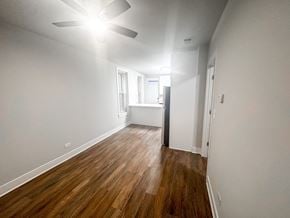 Chicago apartment for rent - A room with a ceiling fan and wooden flooring.