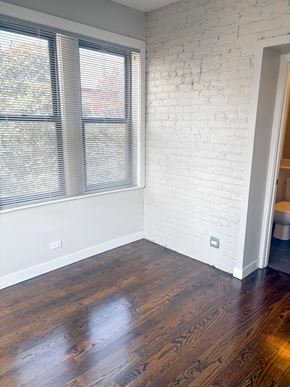 Chicago apartment for rent - A room with a white brick wall and wooden floors.