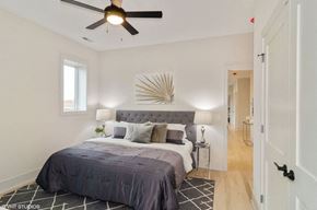 Chicago apartment for rent - A bedroom with a bed, pillows, a ceiling fan, and a wall art piece.