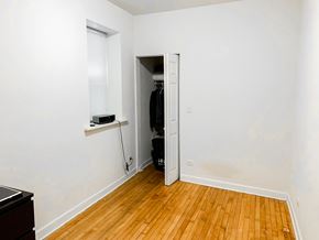 Chicago apartment for rent - A room with a wooden floor and a white wall with a doorway leading to another room.