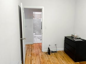 Chicago apartment for rent - A room with a black dresser and a wooden floor.