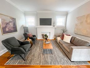 Evanston apartment for rent - A living room with a grey couch, a black chair, and a fireplace.