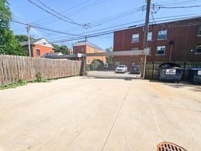 Chicago apartment for rent - a driveway with a fence and brick buildings on either side of it