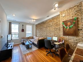 Chicago apartment for rent - A living room with a brick wall and a guitar hanging on it.
