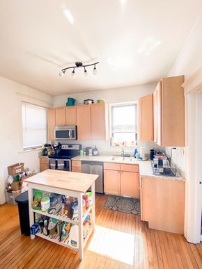 Chicago apartment for rent - A kitchen with wooden floors and a table with a black trash can underneath it.