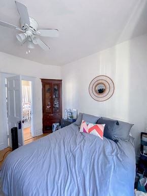Chicago apartment for rent - A bedroom with a bed, a ceiling fan, and a mirror on the wall.
