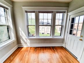 Chicago apartment for rent - A room with a white door and a window showing a view of a building with a black roof.