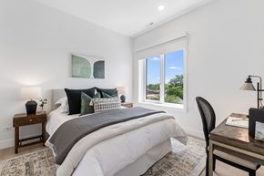 Chicago apartment for rent - A bedroom with a large bed and a window overlooking a green landscape.