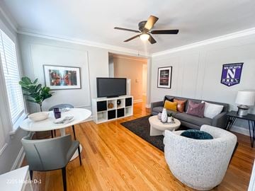 Evanston apartment for rent - A living room with a white sofa, a white coffee table, a grey chair, a white table and a TV.