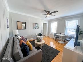 Evanston apartment for rent - A living room with a grey couch and a ceiling fan.
