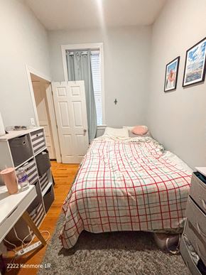 Chicago apartment for rent - A bedroom with a bed, a desk, and a window with a curtain.