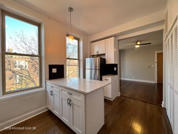 Chicago apartment for rent - A kitchen with white cabinets and a black fridge.