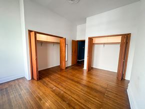 Chicago apartment for rent - A room with wooden floors and white walls with three open doors.