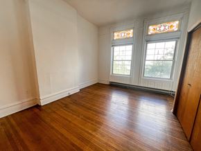 Chicago apartment for rent - A room with wooden floors and two stained glass windows.