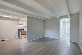 Denver apartment for rent - A spacious room with wood flooring and a kitchenette in the corner.