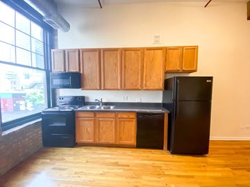 Chicago apartment for rent - A kitchen with wooden cabinets and black appliances.