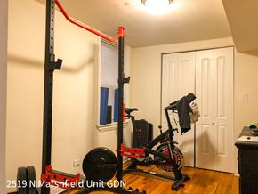 Chicago apartment for rent - A home gym with a squat rack, a weight bench, a barbell and a weighted wheel.