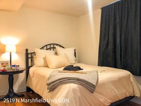 Chicago apartment for rent - A bedroom with a bed, pillows, a nightstand, and a lamp.