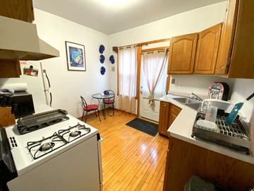 Chicago apartment for rent - A kitchen with a stove, sink, and a dining table with chairs.