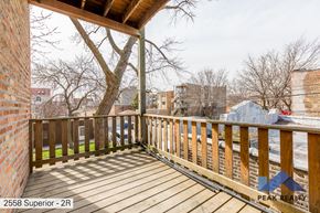 Chicago apartment for rent - A wooden deck with a railing and a tree in the background.