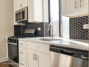 Chicago apartment for rent - A kitchen with white cabinets and a black and white backsplash.