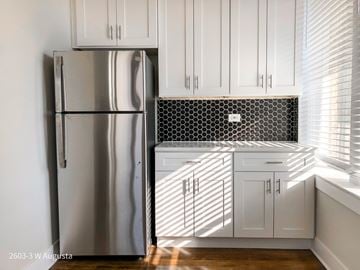 Chicago apartment for rent - A kitchen with white cabinets and a stainless steel refrigerator.