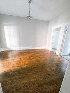 Chicago apartment for rent - A room with a wooden floor and a light hanging from the ceiling.