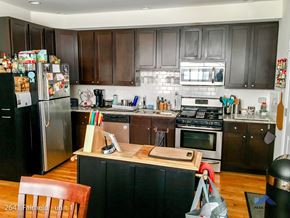 Chicago apartment for rent - A kitchen with a black fridge and brown cabinets.