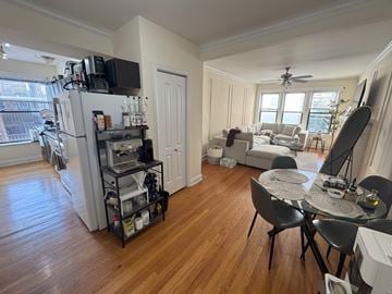 Chicago apartment for rent - A kitchen with a refrigerator, a dining table with chairs, and a living room with a couch.