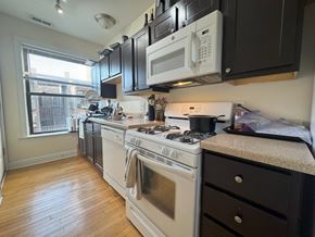 Chicago apartment for rent - A kitchen with black cabinets and white appliances.
