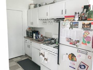 Chicago apartment for rent - A kitchen with white appliances and a refrigerator covered in magnets and decorations.