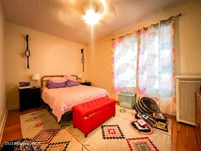 Chicago apartment for rent - A bedroom with a bed, a red ottoman, and a rug with a geometric pattern.