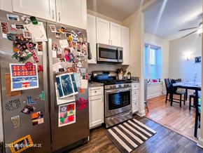 Chicago apartment for rent - A kitchen with a refrigerator covered in magnets and a striped rug on the floor.